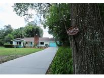 Charming single-story home featuring a brick chimney, turquoise trim, and a well-manicured front yard at 1405 Periwinkle Ave, Deland, FL 32724