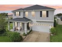 Charming two-story home showcasing a covered front porch, two-car garage, and beautifully landscaped front yard at 2215 Upland Ln, Apopka, FL 32712