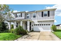 Charming two-story home features a two-car garage, well-manicured lawn, and covered front porch at 2215 Upland Ln, Apopka, FL 32712