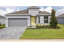 Charming single-Gathering home with a yellow front door, gray brick driveway, and manicured lawn at 2533 Raghav Trl, Tavares, FL 32778