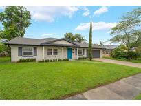 Charming single-story home featuring a well-manicured lawn, a blue front door, and an attached two-car garage at 3902 Brandeis Ave, Orlando, FL 32839