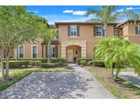 Charming two-story townhome featuring a brick driveway, lush landscaping and a welcoming arched entryway at 3938 Calabria Ave, Davenport, FL 33897