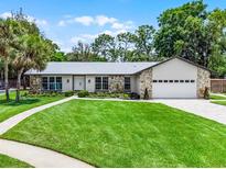 Charming home featuring a lush green lawn, stone accents, and a well-manicured landscape that adds to its curb appeal at 107 Laurel Oak Dr, Longwood, FL 32779