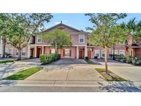 Charming townhome featuring a well-maintained lawn and colorful exterior with mature landscaping at 2343 Caravelle Cir, Kissimmee, FL 34746