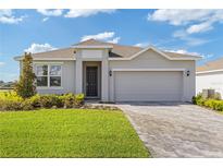Charming single-story home featuring a well-manicured lawn and a gray brick driveway leading to an attached garage at 3144 Suraj Cir, Tavares, FL 32778