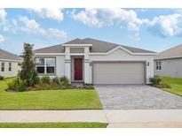 Charming single-story home featuring manicured landscaping and a brick-paved driveway leading to an attached two-car garage at 3144 Suraj Cir, Tavares, FL 32778