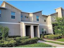 Modern two-story townhouse featuring a neutral color scheme, well-maintained landscaping, and a welcoming covered entrance at 456 Ocean Course Ave, Davenport, FL 33896