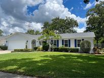 Charming home featuring a manicured front lawn, blue shutters and well maintained landscaping at 7011 Archwood Dr, Orlando, FL 32819