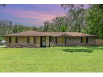 Charming brick home with a well-manicured lawn, mature trees, and a cozy, inviting appeal at 7205 June Bug Ln, Orlando, FL 32818