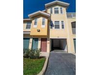 Charming yellow townhouse with garage, well-manicured landscaping, and inviting front entrance at 12106 Poppy Field Ln # 107, Orlando, FL 32837