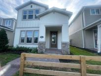 Charming two-story home featuring a welcoming front porch with stone accents and a well-manicured lawn at 1354 Twelve Oaks Rd, St Cloud, FL 34771