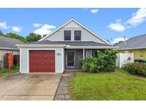Charming home with a red garage door, inviting front porch, and lush landscaping at 1413 Brookebridge Dr, Orlando, FL 32825