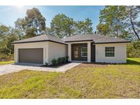 Charming single-story home featuring a gray brick walkway, a two-car garage, and well-manicured landscaping at 14930 Sw 66Th Ave Rd, Ocala, FL 34473