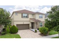 Charming two-story home featuring a brown roof, stone accents, a two-car garage, and a well-manicured front yard at 1505 Nassau Point Trl, Kissimmee, FL 34747