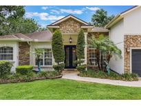 Beautiful front entrance with stone accents, manicured landscaping, and a custom iron door at 1874 Royal Majesty Ct, Oviedo, FL 32765