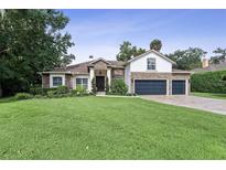 Charming two-story home featuring a stone facade, manicured lawn, and a spacious three-car garage at 1874 Royal Majesty Ct, Oviedo, FL 32765