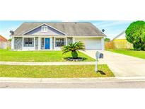 Charming home featuring a well-manicured lawn, stone accents, and a vibrant blue front door at 3038 Golden Rock Dr, Orlando, FL 32818
