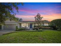 Charming single-story home with a well-manicured lawn and inviting curb appeal under a gorgeous sunset sky at 676 Dunblane Dr, Winter Park, FL 32792