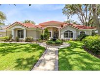 Charming home with a beautiful red tile roof, lush lawn, landscaped yard, and inviting walkway leading to the front door at 718 Glen Eagle Dr, Winter Springs, FL 32708