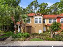 Inviting two-story townhome with a terra cotta roof, lush landscaping, and tall palm trees, creating a welcoming curb appeal at 8507 Crystal Cove Loop, Kissimmee, FL 34747