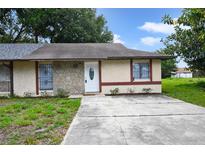 Charming single-story home featuring a stone facade, white door, and concrete driveway at 1447 Candlewyck Dr, Orlando, FL 32807