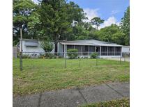 Charming single-story home features a screened front porch and a spacious front yard with chain link fence at 1525 Hilltop Rd, Casselberry, FL 32707