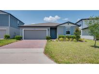 Charming single-story home featuring a well-manicured lawn, brick driveway, and a cozy, inviting entrance at 17363 Million Lakes Ct, Clermont, FL 34714