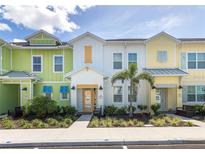 Brightly painted townhomes with colorful accents and well-maintained landscaping create a cheerful street view at 2923 Castaway Ln, Kissimmee, FL 34747