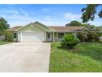Charming one-story home with well-maintained lawn and a two car garage on a bright day at 6906 Sawmill Blvd, Ocoee, FL 34761