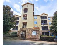 Multi-story condo building with stone facade, balconies and lush surrounding trees at 8020 Tuscany Way # 6307, Davenport, FL 33896
