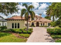 Stunning Mediterranean-style home with a tile roof, lush landscaping, and a circular driveway at 9253 Tibet Pointe Cir, Windermere, FL 34786