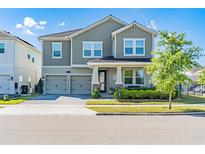 Charming two-story home features a two-car garage, landscaped yard, and inviting front porch at 11479 Satire St, Orlando, FL 32832