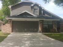 Charming two-story home featuring a brick and gray wood exterior with a two-car garage and a well-maintained front yard at 2181 Wekiwa Oaks Dr, Apopka, FL 32703