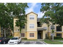 Inviting condo building with three stories, beige paint and black stairs, complemented by mature trees and ample parking at 2598 Robert Trent Jones Dr # 1030, Orlando, FL 32835