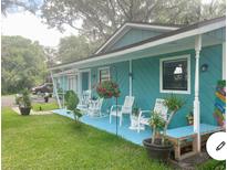 Inviting front porch with rocking chairs and colorful beach-themed decor and freshly cut lawn at 400 Palm Ave, Ormond Beach, FL 32174