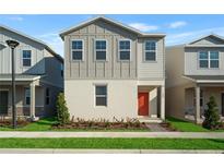 Charming two-story home featuring neutral tones, a red front door, and manicured landscaping at 558 Orient Ave, Debary, FL 32713