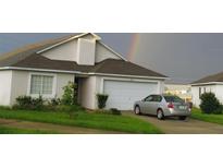 Charming home with a two-car garage, landscaped front yard and a rainbow behind at 602 Hillcrest Dr, Davenport, FL 33897