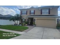 Two-story home featuring a manicured lawn, two-car garage, and stone pillar accents at 10549 Cypress Trail Dr, Orlando, FL 32825