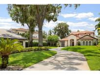 Charming Mediterranean-style home featuring a circular driveway, lush green lawn, and mature trees draped with Spanish moss at 11018 Lake Butler Blvd, Windermere, FL 34786