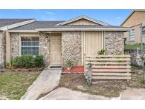 Charming front exterior of a stone-clad home with a well-maintained landscaped entrance and blue sky at 1113 Woodman Way, Orlando, FL 32818
