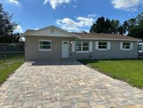 Charming single-story home with a well-manicured lawn and a patterned brick driveway under a sunny blue sky at 1139 Poppy Ave, Orlando, FL 32811