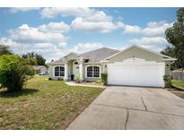 Charming single-story home with a well-manicured lawn, attached two-car garage, and inviting front entrance at 1221 N Brickell Dr, Deltona, FL 32725