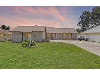 Charming single-story home with a well-maintained lawn and colorful flower garden at 27714 Lois Dr, Tavares, FL 32778