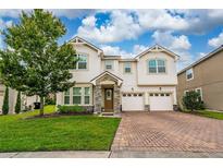 Inviting two-story home with a well-manicured lawn and brick paver driveway at 4952 Longmeadow Park St, Orlando, FL 32811