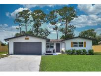 Charming one-story home featuring a gray garage door, manicured lawn, and neat landscaping at 550 Eagle Dr, Daytona Beach, FL 32117