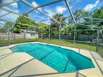 A clear, turquoise pool is surrounded by a screened enclosure and lush greenery, bathed in sunlight at 720 Meadow St, Sanford, FL 32773