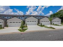 Row of modern townhomes, each featuring an attached single-car garage and manicured landscaping at 8584 Magnificent Ln, Groveland, FL 34736