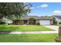 Charming single-story brick home with a well-manicured lawn, beautiful landscaping, and a two-car garage at 985 Willow Run Ln, Winter Springs, FL 32708