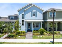 Charming two-story home featuring a welcoming front porch, neat landscaping, and a vibrant blue facade at 10322 Marconi Ave, Orlando, FL 32827