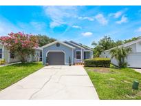 Charming single-story home with light blue siding, gray garage door, landscaped yard, and a concrete driveway at 104 Yorktown Pl, Sanford, FL 32771